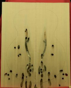 Teredo float log Sitka Spruce Archtop Guitar tonewood planks with mollusk holes and guitar outline.