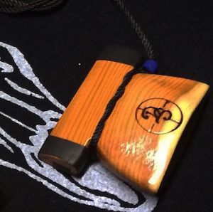 Handcrafted yew wood bell call pendant with polished orange wood pieces and braided cord.