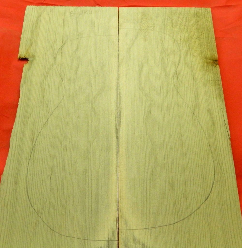 Quartersawn wood planks with pencil outline showing flat top mandolin top body shape.