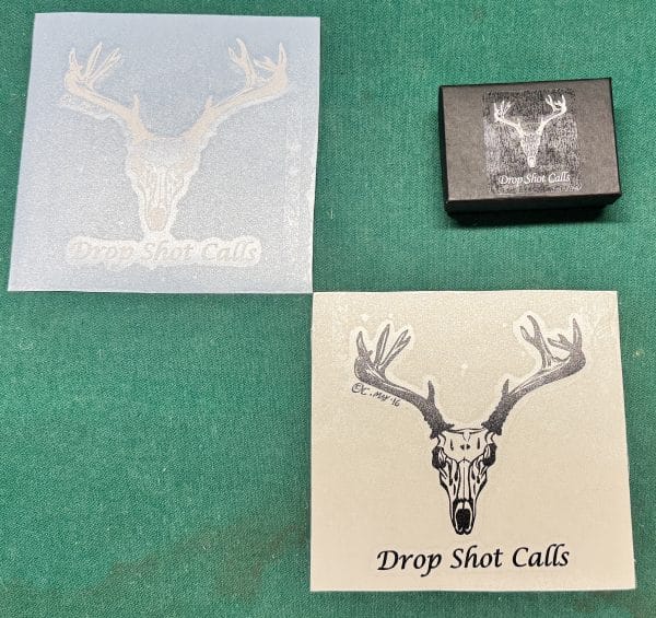 Translucent white Small DropShot Decal with deer skull logo and DropShot Calls text on green surface.